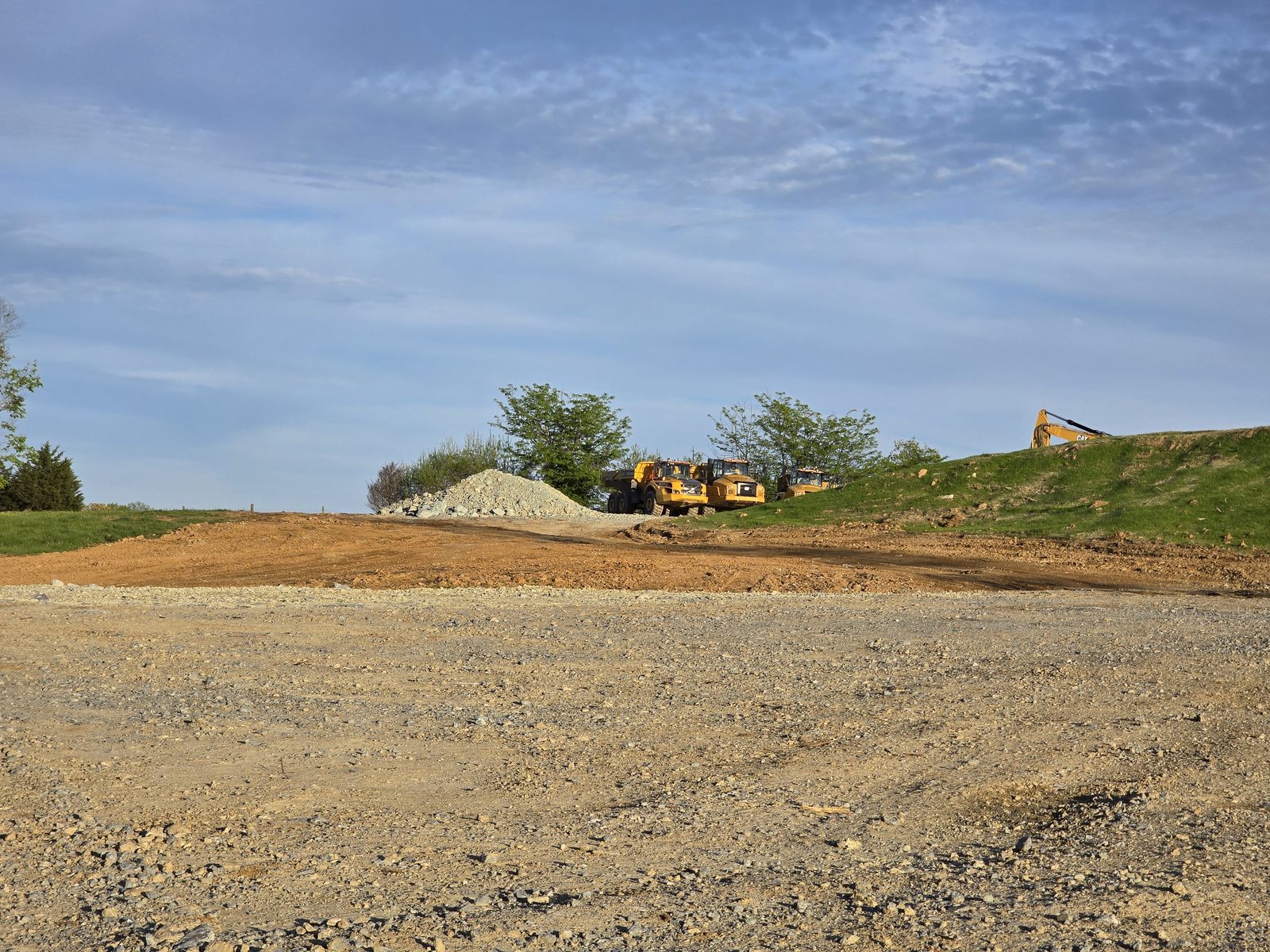 A cleared dirt site with excavators in the distance