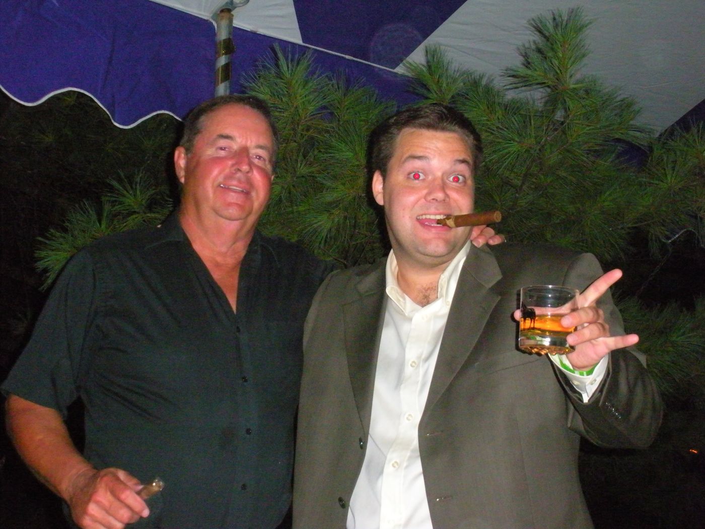 Justin with a cigar and a pour beside a friend