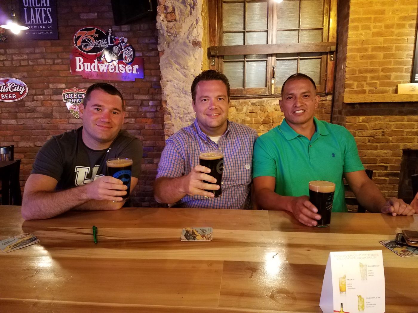 Three friends with pints at a bar