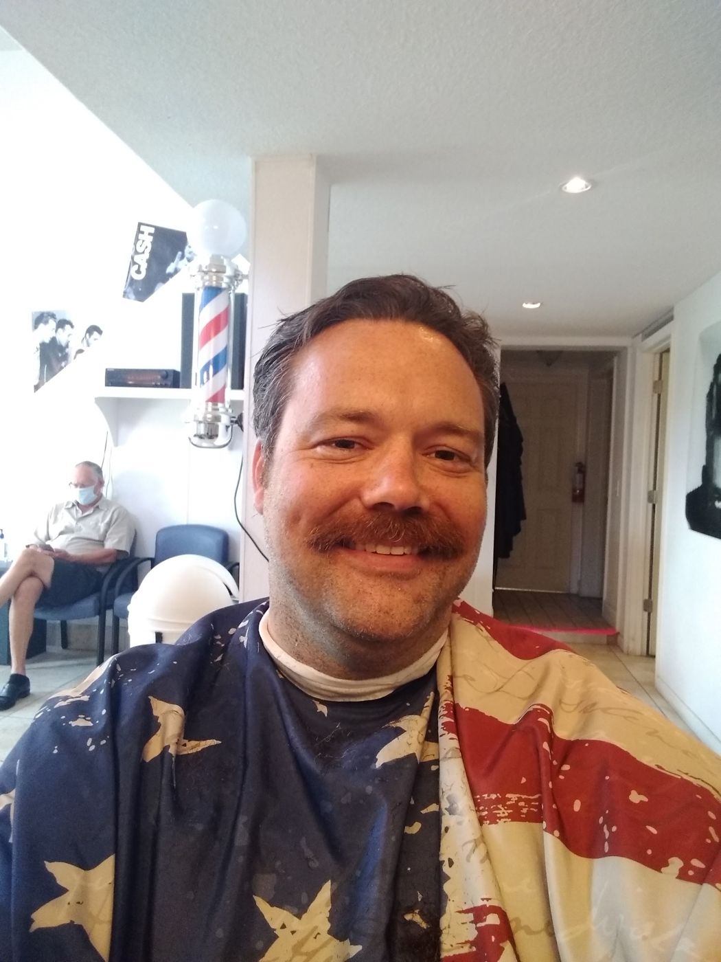 Justin with a mustache in the barber chair