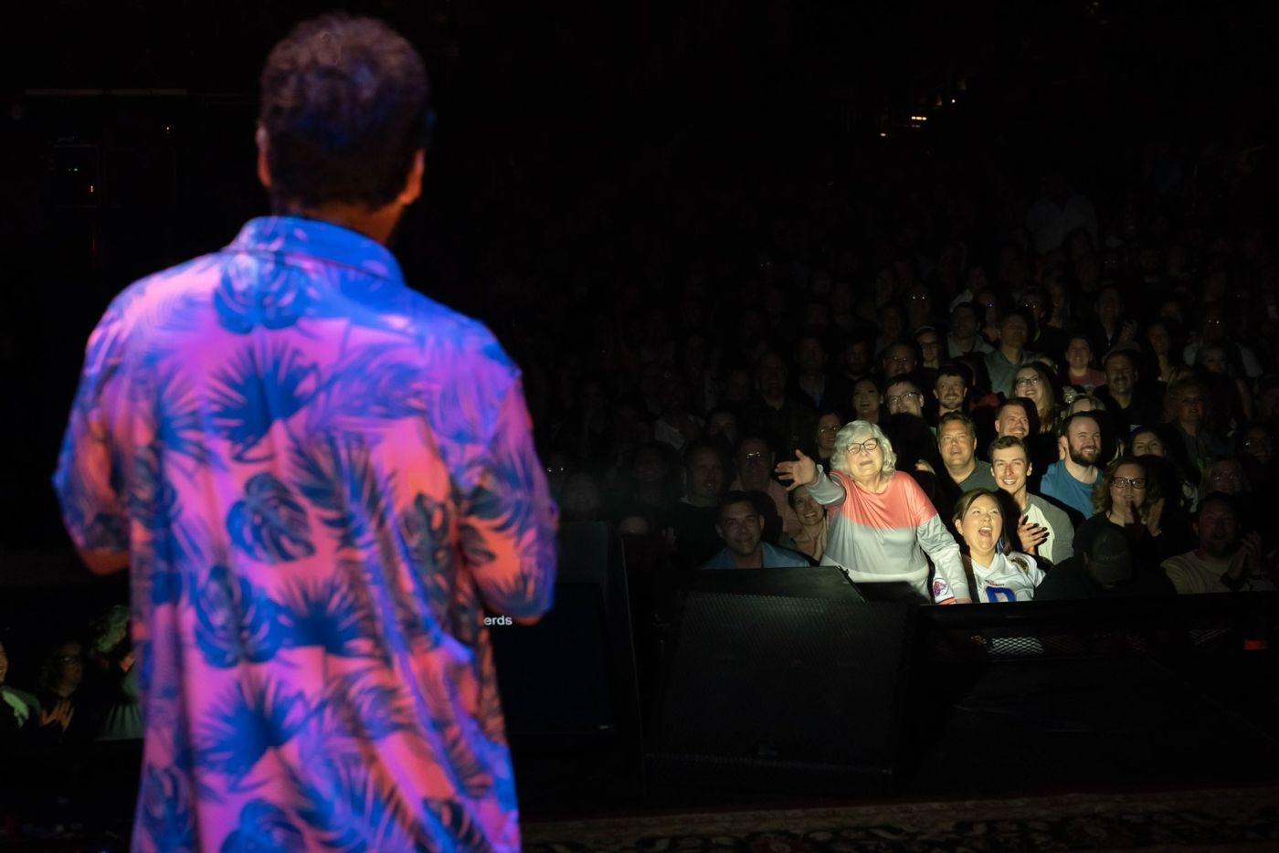 Justin in a loud shirt in front of a packed house