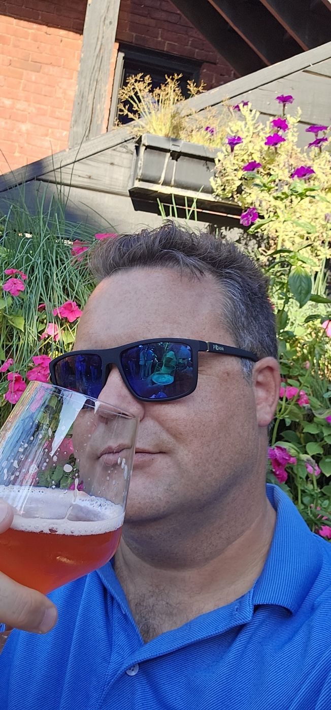 Justin with a drink among the flowers