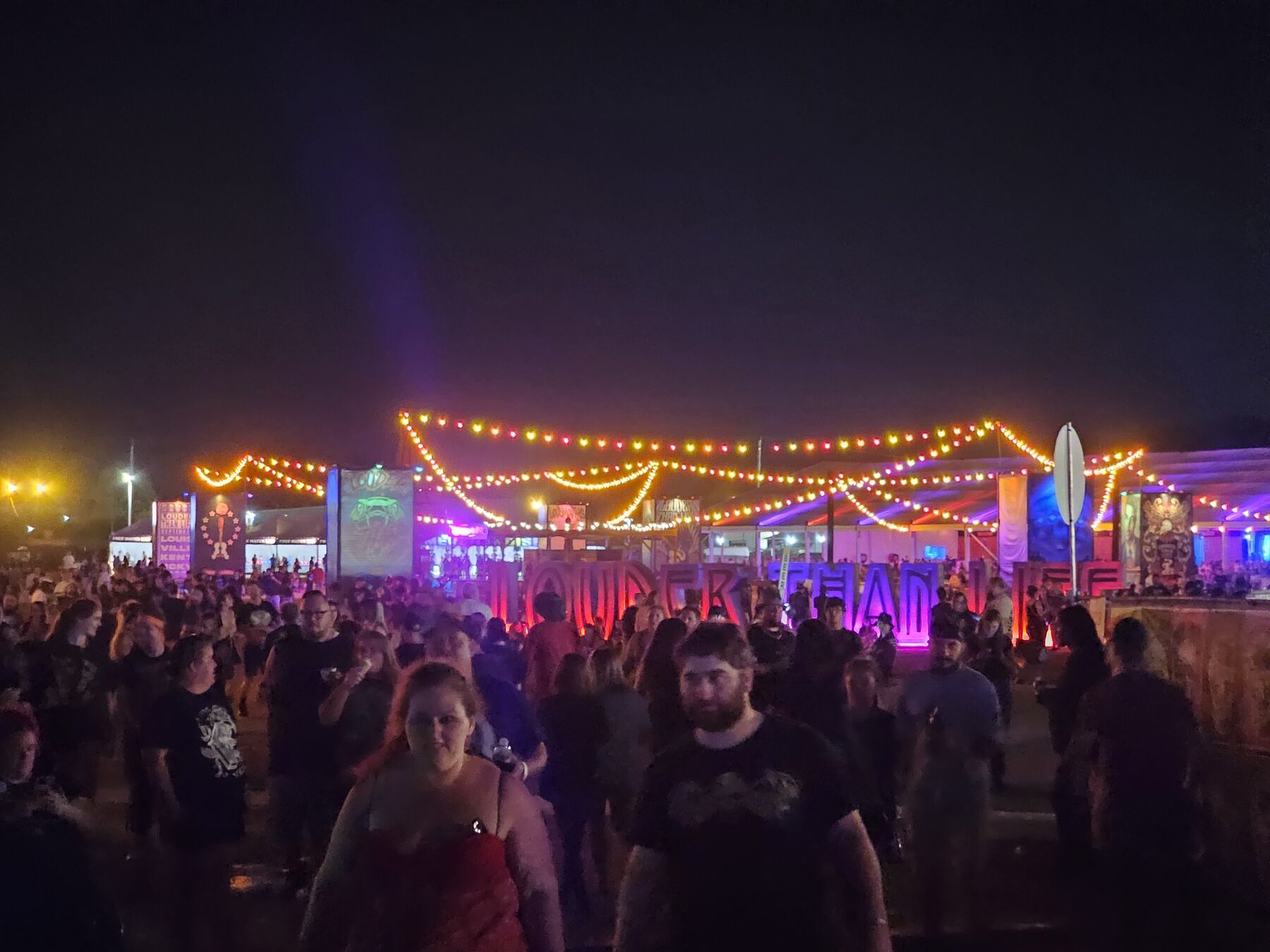 A festival crowd under strings of lights