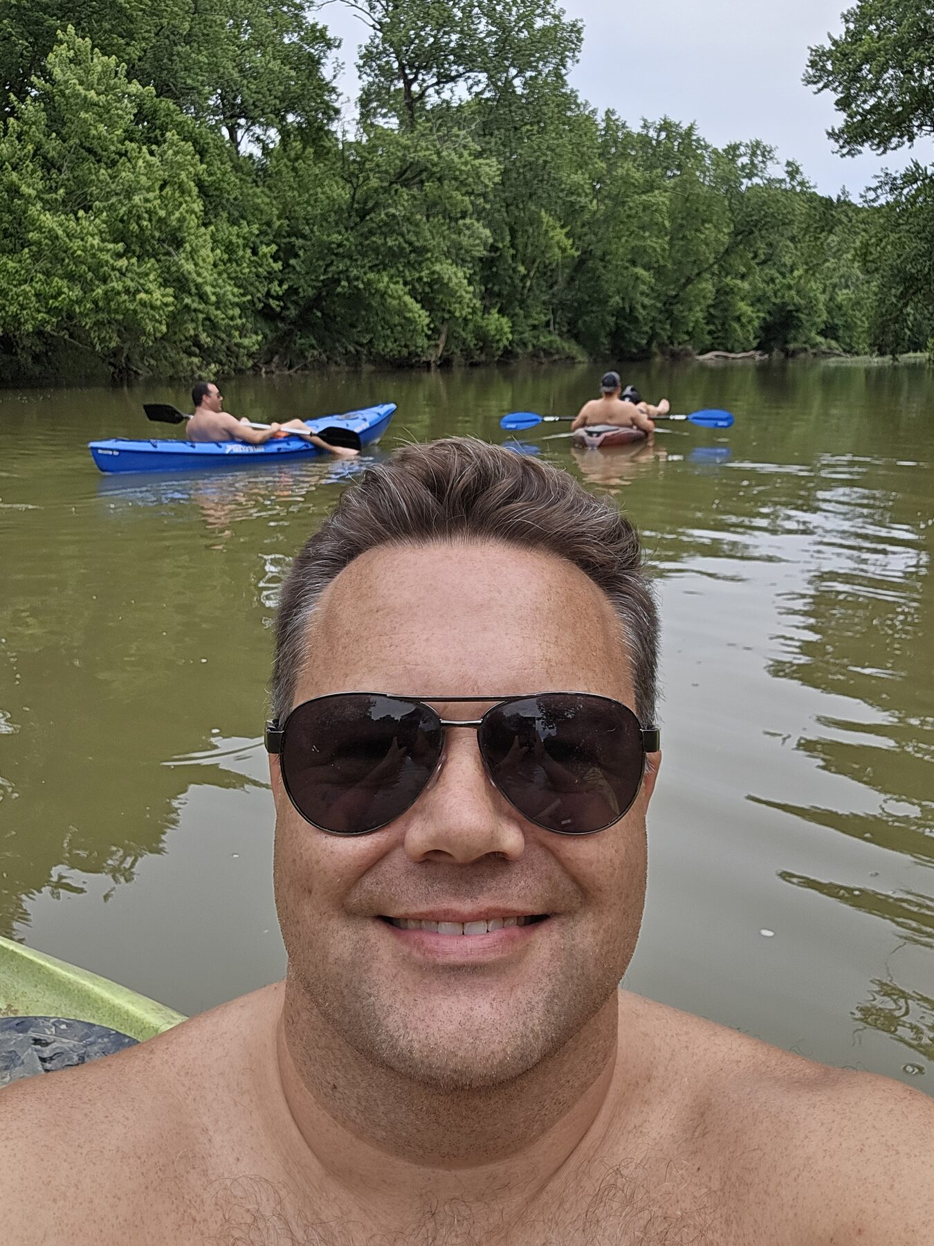 Justin on the river, kayakers behind him